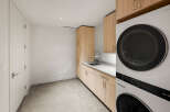This modern laundry room features sleek, light wood cabinetry providing ample storage space.
