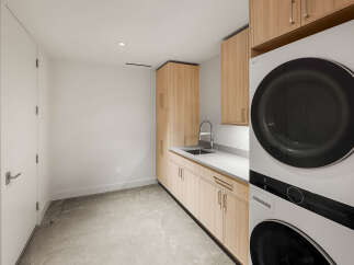 This modern laundry room features sleek, light wood cabinetry providing ample storage space.