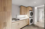 Discover this modern laundry room featuring sleek, light wood cabinetry and a durable quartz countertop.
