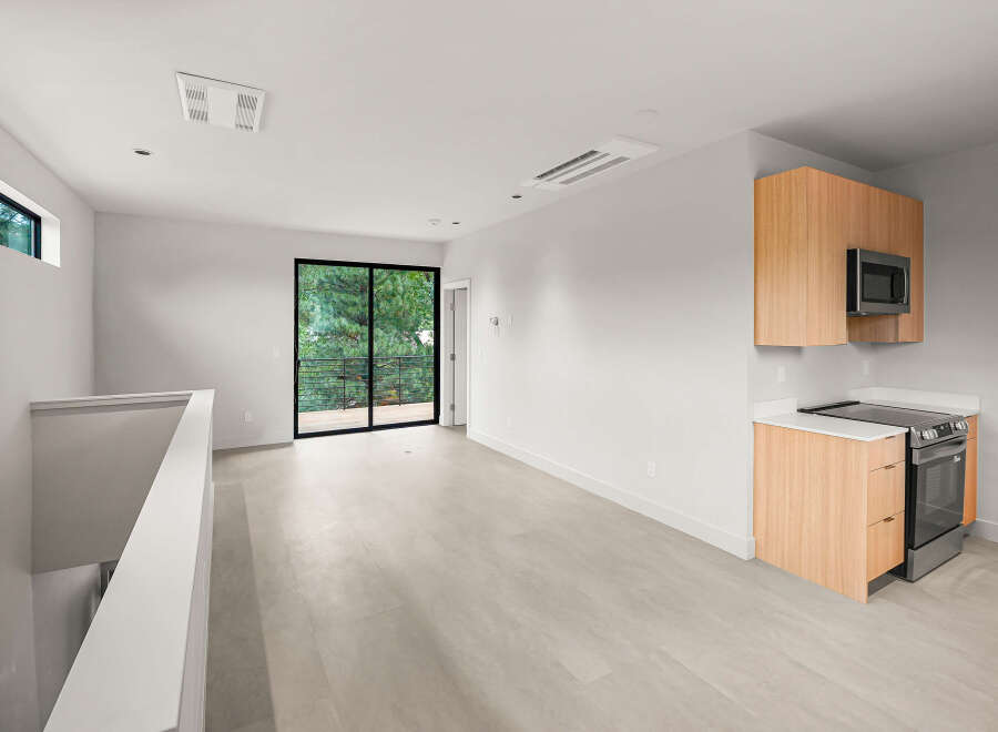Experience modern living in this bright and airy space, featuring a sleek kitchen with stainless steel appliances and ample cabinet storage.