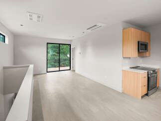 Experience modern living in this bright and airy space, featuring a sleek kitchen with stainless steel appliances and ample cabinet storage.