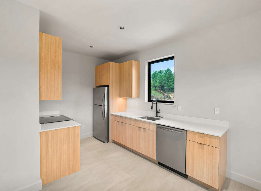 This modern kitchen features sleek, light wood cabinetry paired with crisp white countertops.