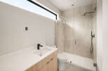 Experience modern luxury in this stunning bathroom featuring a sleek vanity with a black faucet and a spacious glass-enclosed shower with elegant tilework.