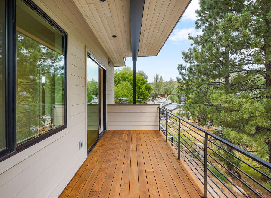 Experience breathtaking views from this modern balcony, featuring a warm wooden deck and sleek metal railings.