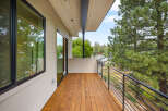 Experience breathtaking views from this modern balcony, featuring a warm wooden deck and sleek metal railings.