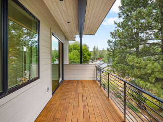 Experience breathtaking views from this modern balcony, featuring a warm wooden deck and sleek metal railings.