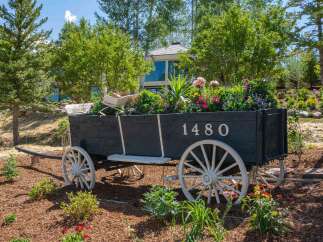 Discover a unique property featuring a charming antique wagon overflowing with vibrant flowers, serving as a picturesque garden accent.