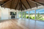 Experience breathtaking mountain views from this stunning living space, featuring a dramatic vaulted wood-beamed ceiling and a modern stone fireplace.