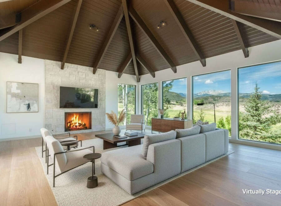 Experience breathtaking mountain views from this stunning living room, featuring a modern fireplace and expansive windows.