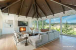 Experience breathtaking mountain views from this stunning living room, featuring a modern fireplace and expansive windows.