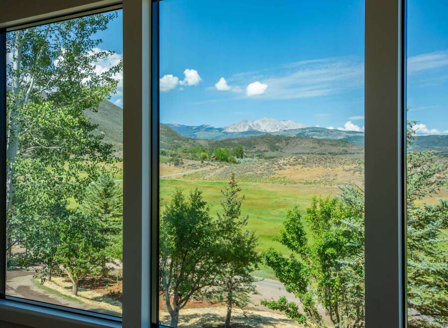 Experience breathtaking mountain views from this stunning property, framed by lush greenery and large windows.