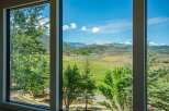 Experience breathtaking mountain views from this stunning property, framed by lush greenery and large windows.