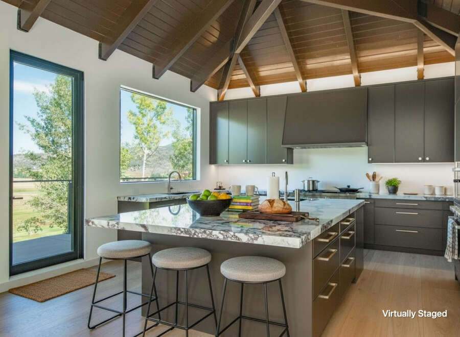 Experience modern luxury in this stunning kitchen, featuring sleek dark cabinetry and a dramatic vaulted wood ceiling.