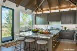 Experience modern luxury in this stunning kitchen, featuring sleek dark cabinetry and a dramatic vaulted wood ceiling.