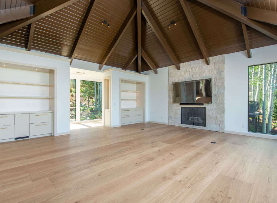 Experience luxury living in this spacious room featuring a vaulted wood-paneled ceiling and a striking stone fireplace.