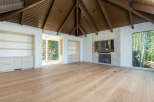 Experience luxury living in this spacious room featuring a vaulted wood-paneled ceiling and a striking stone fireplace.