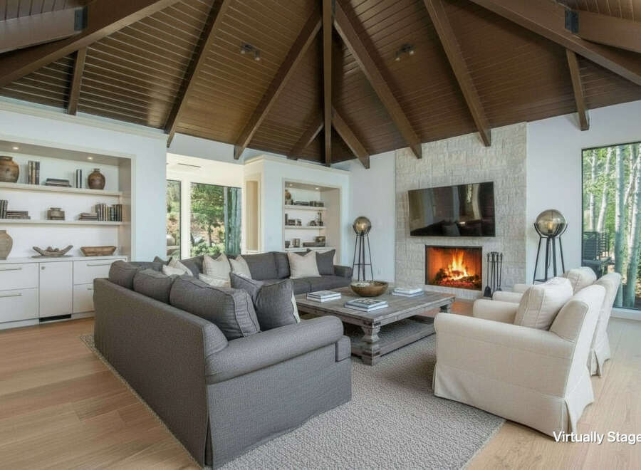 Experience luxurious living in this stunning great room, featuring a soaring vaulted wood-beamed ceiling and a magnificent stone fireplace.