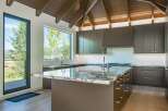 Experience modern luxury in this stunning kitchen, featuring sleek dark cabinetry and a dramatic vaulted wood ceiling.