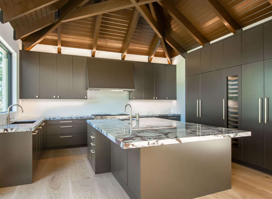 Experience luxury in this modern kitchen featuring sleek, dark cabinetry and stunning marble countertops.