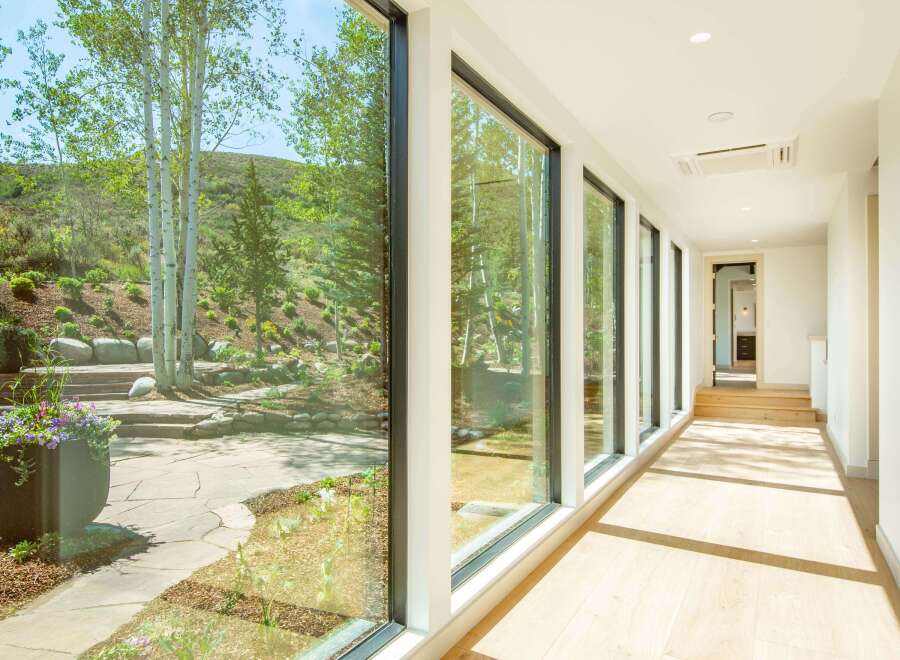 Experience seamless indoor-outdoor living with expansive floor-to-ceiling windows that frame breathtaking views of a lush, natural landscape.