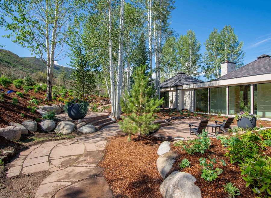 Experience luxury mountain living with this stunning property, featuring a modern home seamlessly integrated into a natural landscape.