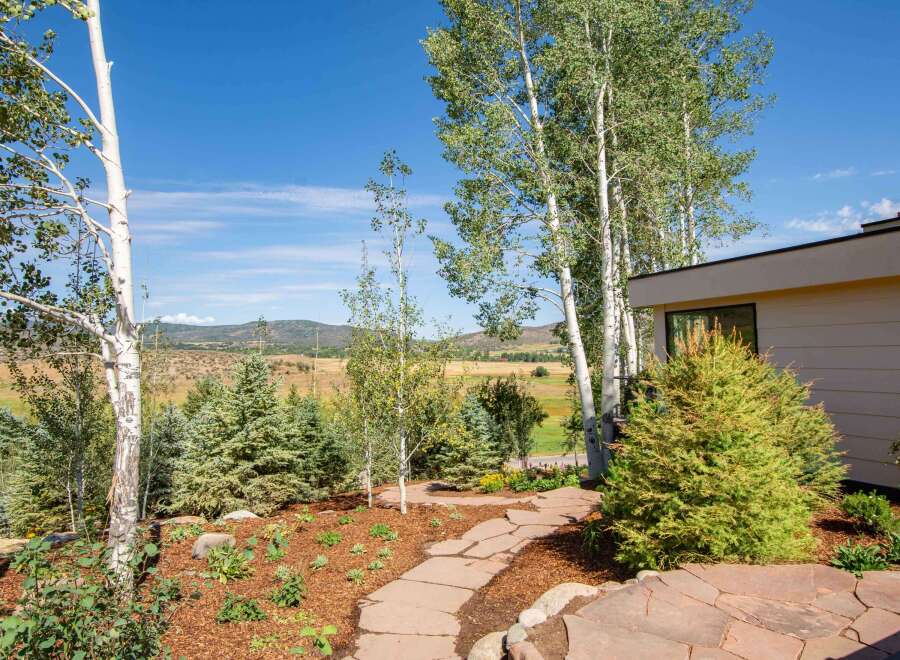 Discover this stunning property featuring a beautifully landscaped yard with a flagstone pathway leading through mature trees and vibrant greenery.