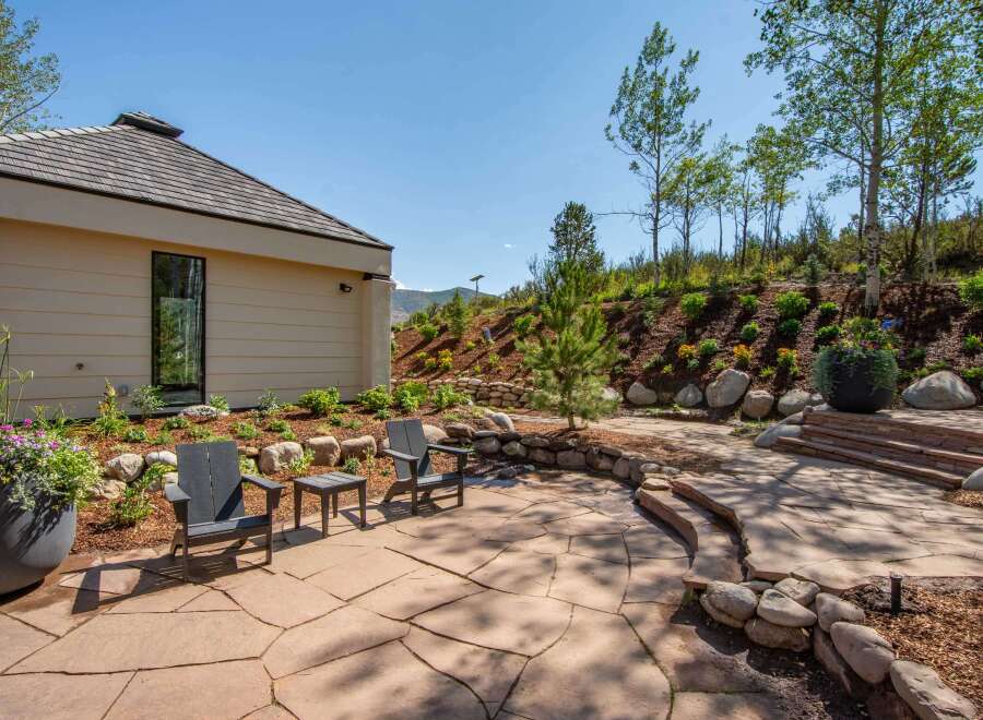 Experience outdoor living at its finest with this beautifully landscaped patio featuring flagstone flooring and a curved stone retaining wall.