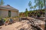 Experience outdoor living at its finest with this beautifully landscaped patio featuring flagstone flooring and a curved stone retaining wall.