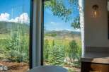 Experience breathtaking mountain views from this stunning property, framed by large windows and lush greenery.