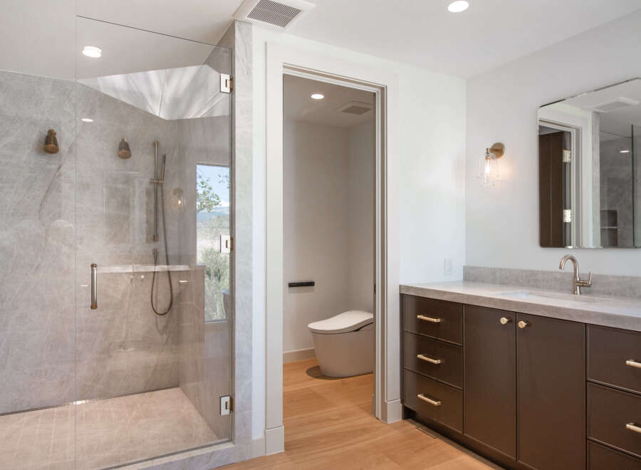 Experience luxury in this modern bathroom featuring a spacious glass-enclosed shower with marble tile and dual showerheads.