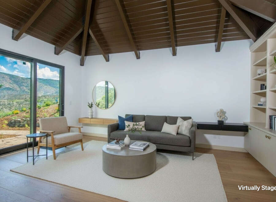 Experience breathtaking mountain views from this stunning living room, featuring a vaulted wood-beamed ceiling and expansive sliding glass doors.