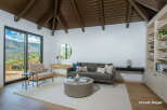 Experience breathtaking mountain views from this stunning living room, featuring a vaulted wood-beamed ceiling and expansive sliding glass doors.