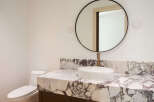 Experience modern luxury in this bathroom, featuring a striking marble vanity top that complements the sleek vessel sink and elegant brass faucet.