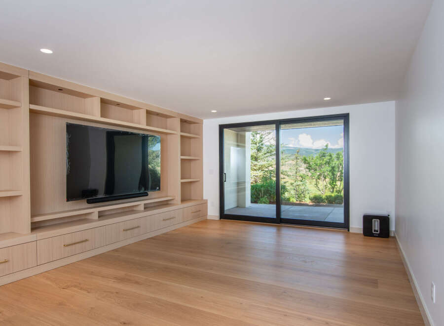 This modern living room features a custom built-in entertainment center with ample shelving and storage, perfect for displaying decor or organizing media.