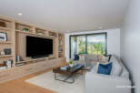 Experience modern living in this spacious living room, featuring a custom built-in entertainment center with ample storage and display shelves.