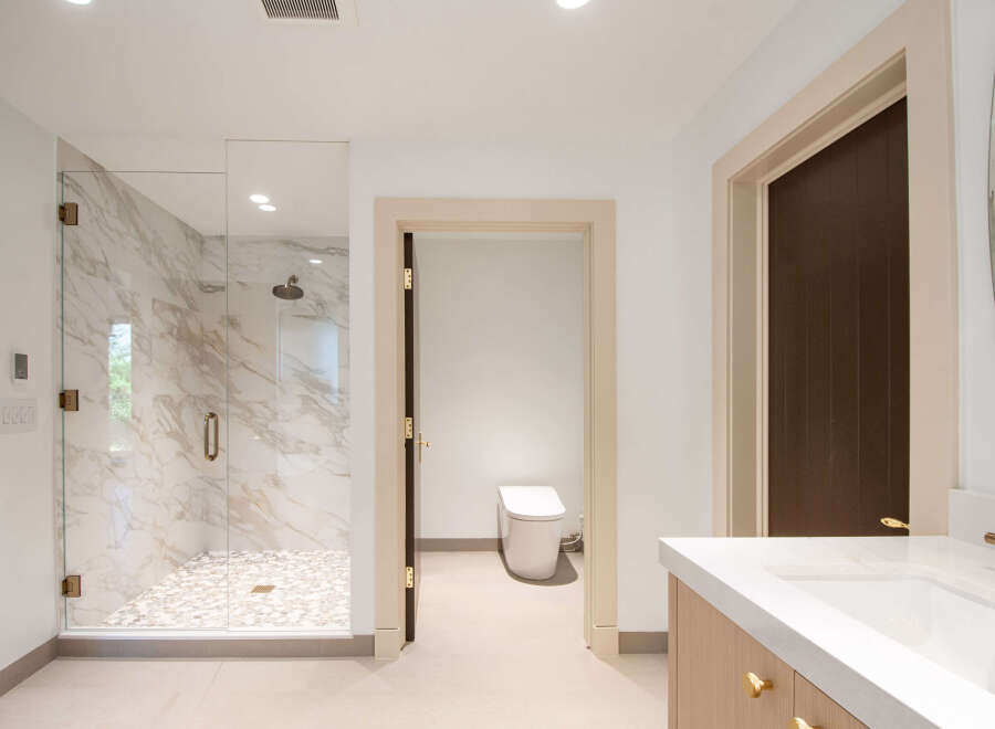 Experience modern luxury in this stunning bathroom featuring a spacious marble shower with a glass enclosure and a sleek, modern toilet.
