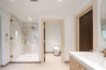 Experience modern luxury in this stunning bathroom featuring a spacious marble shower with a glass enclosure and a sleek, modern toilet.