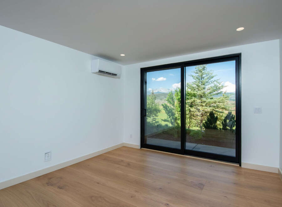 Experience breathtaking mountain views from this spacious room, featuring a large sliding glass door that opens to a lush, green landscape.