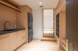 Discover modern convenience in this laundry room, featuring a stacked washer and dryer, a sleek sink with a gooseneck faucet, and ample storage.