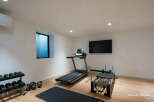 Elevate your fitness routine in this dedicated home gym, featuring a treadmill, pilates reformer, and a full set of dumbbells and kettlebells.