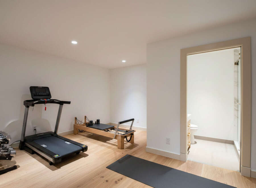 This home features a dedicated fitness space with a treadmill, Pilates reformer, and dumbbells, perfect for your wellness routine.