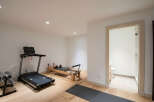 This home features a dedicated fitness space with a treadmill, Pilates reformer, and dumbbells, perfect for your wellness routine.