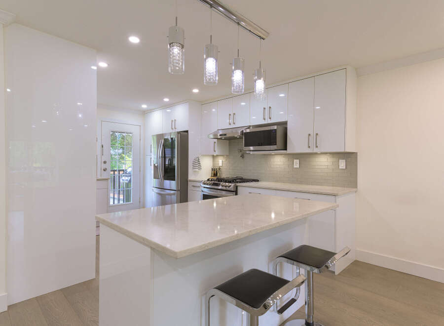 Experience modern living in this stunning kitchen featuring sleek white cabinetry and a spacious island with a marble countertop.