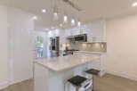 Experience modern living in this stunning kitchen featuring sleek white cabinetry and a spacious island with a marble countertop.