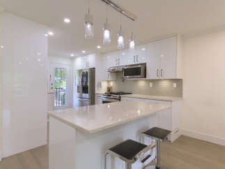 Experience modern living in this stunning kitchen featuring sleek white cabinetry and a spacious island with a marble countertop.