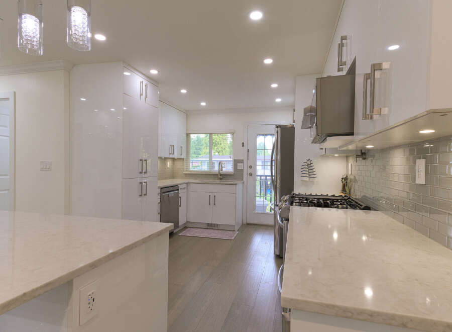 Experience modern luxury in this stunning kitchen, featuring sleek white high-gloss cabinetry and elegant quartz countertops.
