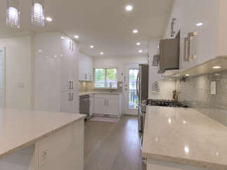 Experience modern luxury in this stunning kitchen, featuring sleek white high-gloss cabinetry and elegant quartz countertops.
