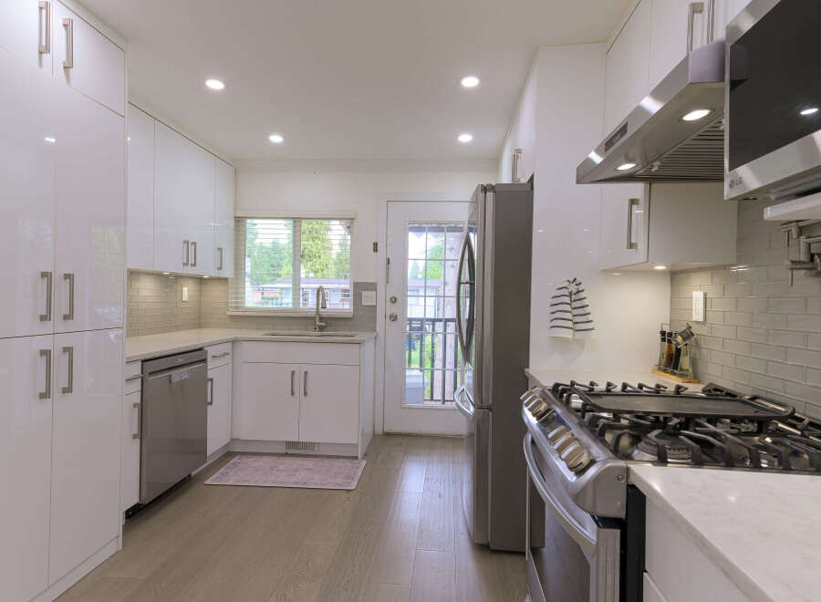 Step into this modern kitchen featuring sleek white cabinetry and a stainless steel appliance suite.