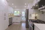 Step into this modern kitchen featuring sleek white cabinetry and a stainless steel appliance suite.