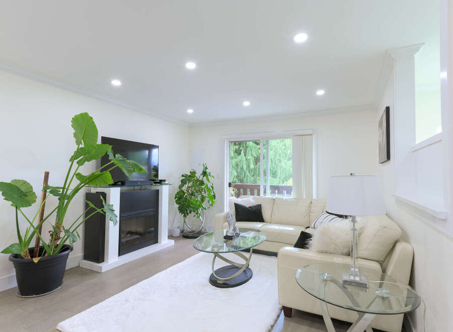 Experience modern living in this bright and airy living room, featuring a sleek fireplace and a large flat-screen TV.